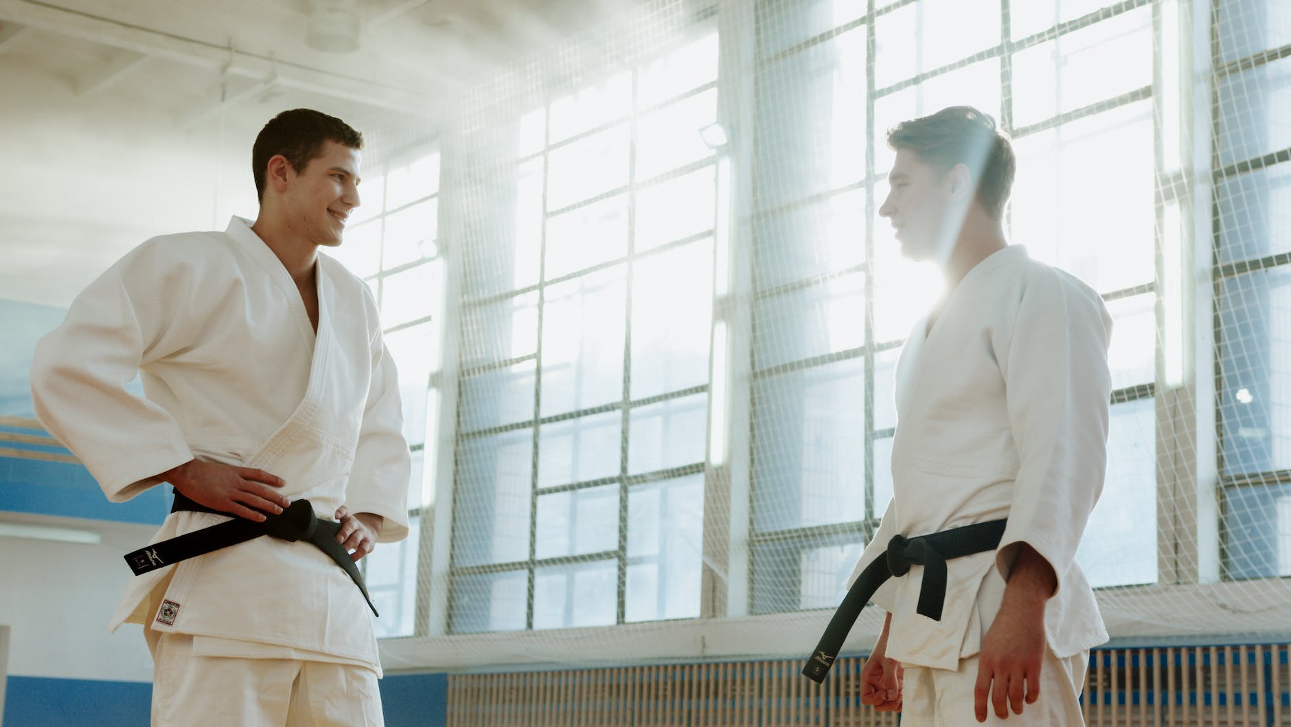 men wearing white uniform with black belt standing face to face while smiling at each other